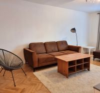 Living room of a two-room apartment with a brown sofa and a floor with a wooden decor.