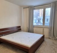 A bedroom with gray curtains, a large window, and a bed in a two-room apartment.