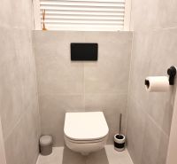 Bathroom in a 2-room apartment with a modern wall-hung toilet on light tiles.
