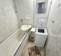 A bathroom with a bathtub, toilet, washing machine, and mirror in a 3-room apartment.