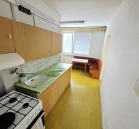 A kitchen in a 3-room apartment with simple equipment, wooden cabinets, and a dining area.