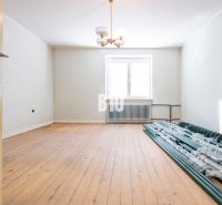A room in a family house with a wooden decor floor and a pile of sticks by the window.