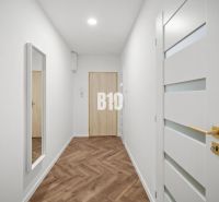 Hallway of a 3-room apartment with a wooden decor floor and a mirror on the wall.