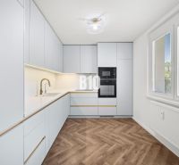 A kitchen with modern equipment and a wooden decor floor in a 3-room apartment.
