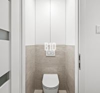 A toilet with white doors and tiles in a 3-room apartment.