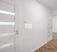 White interior of a 3-room apartment with wood-patterned flooring and elegant doors.