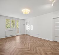 A spacious room with a wooden decor floor in a 3-room apartment.