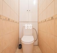 A toilet with beige tiles in a studio apartment, practical design and storage space.