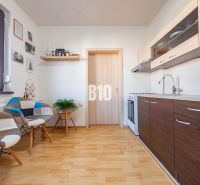A kitchen in a one-room apartment with a wooden decor floor and modern furniture.
