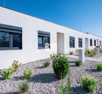 A family house in Nitra with a white facade, black windows, and a landscaped garden.
