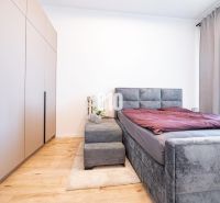 A bedroom in a family house with a bed, wardrobe, and wooden decor flooring.