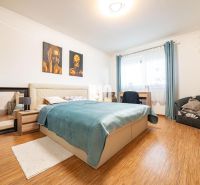 Bedroom in a family house with a bed, mirror, and wooden decor flooring.
