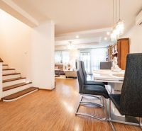 Dining area with wood-patterned flooring and a staircase in a family house.