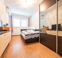 Bedroom in a family house with a wooden decor floor, wardrobe, and television.