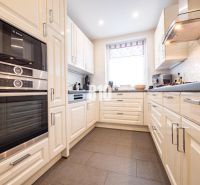 A kitchen with white cabinets and appliances, a wood-decor floor, in a family house.