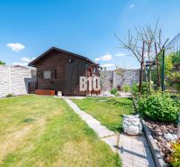 A garden of a family house in Nitra with a garden shed, green lawn, and decorations.