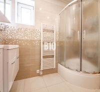 A bathroom in a family house with a corner shower and light tiles.