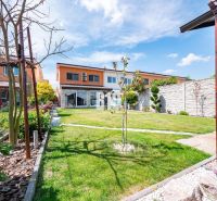 A garden at a family house in Nitra with a lawn, flowers, and a terrace.