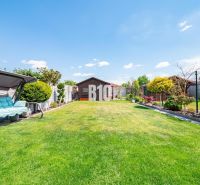 A garden of a family house in Nitra with a manicured lawn and a garden swing.