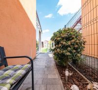 A family house in Nitra with a walkway, a bench, and a garden lined with greenery.