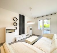 Living room in a two-room apartment with a wooden decor floor and white furniture.