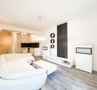 A bright living room in a two-room apartment with a comfortable sofa and a wooden decor floor.