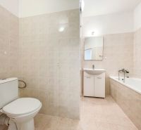 Bathroom in a 2-room apartment with a sink, bathtub, and white tiles.