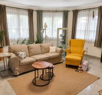 Living room in a family house with a sofa, a yellow armchair, and a bookshelf.