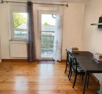 Interior of a family house with a wood-decor floor, table, books, and a plastic entrance.