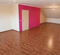 Living room in a family house with a wooden decor floor and a pink wall.