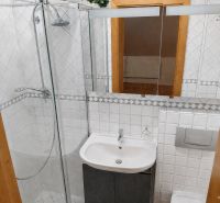 A bathroom in a family house with white tiles and a shower corner.