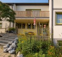 A family house in Podersdorf am See with stone stairs and a garden full of flowers.