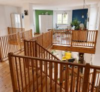 The interior of a family house with a wooden decor floor and wooden railing.
