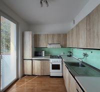 A kitchen in a 3-room apartment with a wood-patterned floor and direct access to the balcony.