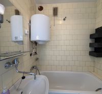A bathroom in a 3-room apartment with a bathtub, a sink, and a water heater.