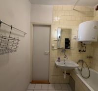 A bathroom in a 3-room apartment with a sink, a bathtub, and a water heater on the wall.
