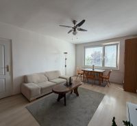 Living room in a three-room apartment with a wooden decor floor and a dining table.