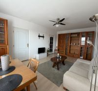 A living room of a three-room apartment with wooden furniture and a floor with a wooden decor.