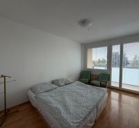 A bedroom in a 3-room apartment with a wooden decor floor, a bed, and chairs.