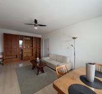 Living room with wood-patterned flooring, a sofa, and a dining table in a three-room apartment.
