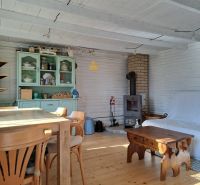 The interior of the cottage with a wood-patterned floor, wooden furniture, and a stove.