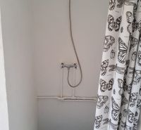 Shower corner with a white curtain featuring a butterfly motif in the cabin.
