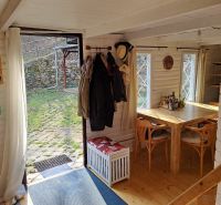 Wooden table and chairs in a cottage with a garden view.