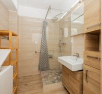 Bathroom with a shower and a floor with a wooden decor in a 3-room apartment.