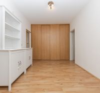 A hallway in a 3-room apartment with a white cabinet and a wooden decor floor.