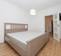 A bedroom with a bed and a wooden decor floor in a 3-room apartment.