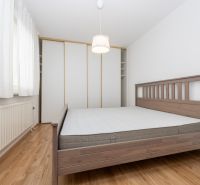 A bedroom in a three-room apartment with a wooden bed and a floor with a wooden decor.
