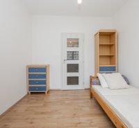 A simple room with a bed, a cabinet, and a floor with a wooden decor in a three-room apartment.