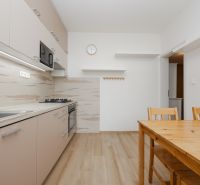 A kitchen in a 3-room apartment with a wooden decor floor and wooden furniture.