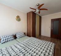 A bedroom in a 3-room apartment with a double bed, a built-in wardrobe, and a floor with a wooden decor.